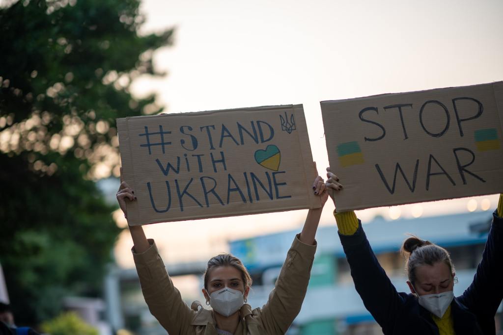 Two women protesting and holding signs that read #Stand with Ukraine and Stop War